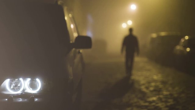 The car with a headlight on the walking man background. evening night time
