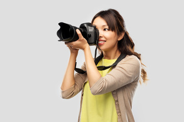photography, profession and people and concept - happy asian female photographer with digital camera