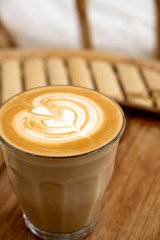 Hot latte in a wooden tray on a bamboo table