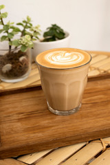 Hot latte in a wooden tray on a bamboo table