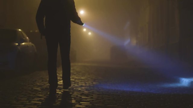 The man with a flashlight walking on the night street