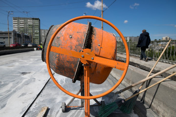 orange concrete mixer prepares cement mortar