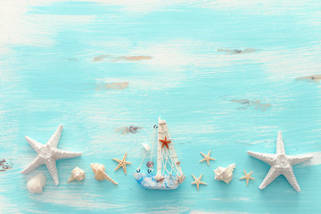 Fototapeta na wymiar vacation and summer concept with vintage boat, starfish and seashells over pastel blue wooden background. Top view flat lay