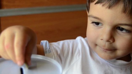 cute two years old saving money, putting coins in metal bank