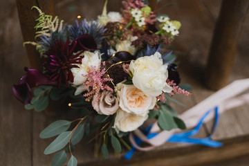 Beautiful modern bridal bouquet of colorful fresh flowers with sikl ribbons. Classic wedding traditional accessory.