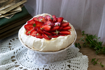 Pavlova meringue homemade cake with strawberries and cream on the background of an old photo album. Rustic style.