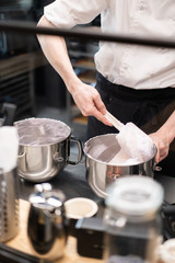 Master chef prepares a sweet dessert for the production of sweets. Mixing dough and cream for the cake in a deep bowl.