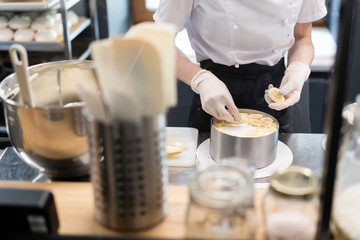 Master chef prepares a sweet dessert for the production of sweets. Mixing dough and cream for the cake in a deep bowl.