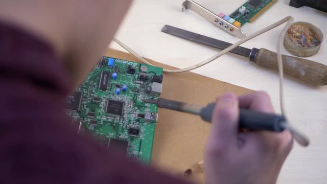 Student soldering electronic components at home office