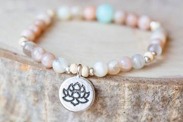 Mineral stone sun stone and lotus pendant bead bracelet on natural wooden background