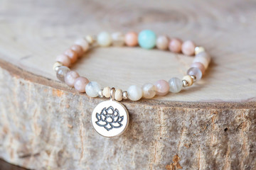 Mineral stone sun stone and lotus pendant bead bracelet on natural wooden background