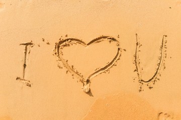 Obraz na płótnie Canvas Feet stand near the sign - I heart of you. Summer vacation sand beach inspire to travel on Valentines day. Romantic travel for love couples or family holidays. Relaxing sign I love you on yellow sand
