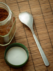 Coffee spoon lays near the jar of coffee and its cap