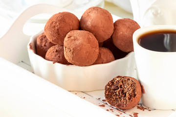 Homemade dark chocolate vegan truffles with nuts plate light background. Selective focus.