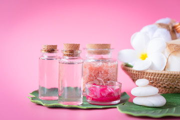 Obraz na płótnie Canvas Spa Himalayan salt,red candle,milk and rose liquid.soap,white towel,flowers ,zen stone set on green leaves over pink background