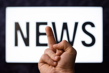 Showing middle finger to screen with news program having no desire to hear bad news