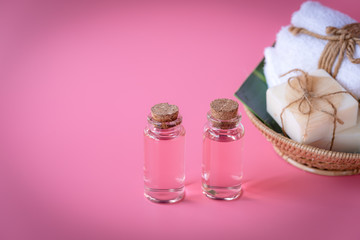 Fototapeta na wymiar Spa wellness concept,rose liquid bottle,milk soap,white towels in wooden tray on pink background