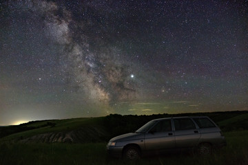 Fototapeta na wymiar View of the Milky Way over the car travelers. Bright stars of the night sky. Astrophotography with a long exposure.