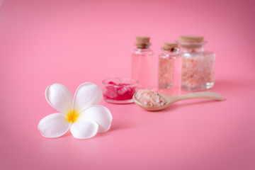Obraz na płótnie Canvas Spa wellness concept,white plumeria flower ,red candle,sea salt and rose liquid soap bottle on pink background