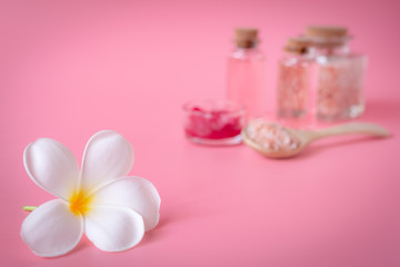 Fototapeta na wymiar Spa wellness concept,white plumeria flower ,red candle,sea salt and rose liquid soap bottle on pink background