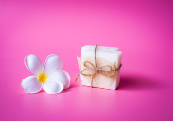 Beautiful white Plumeria flower and milk soap on pink background