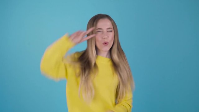 Funny cute girl. Dancing funny dancing on an isolated blue background. . Young student rejoices and weighs. 4K