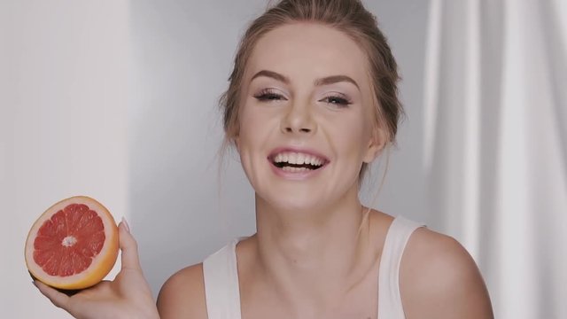 gorgeous woman closing her eye with half of grape fruit and sending kiss