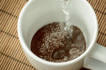 Pouring boiling water to the cap with coffee and sugar. Making coffee in the morning.