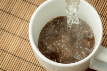 Pouring boiling water to the cap with ground coffee and sugar. Making coffee in the morning. Refreshing in the morning.