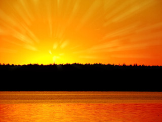 Orange light with sun rays and dark forest on river