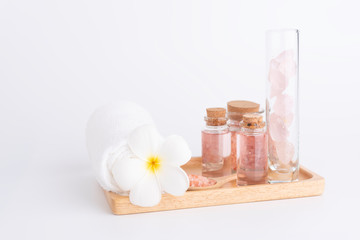Spa and beauty treatment with rose  liquid soap,pink Himalayan salt,rose quatz stones,white towel and Plumeria  flowera on wooden tray over white  background