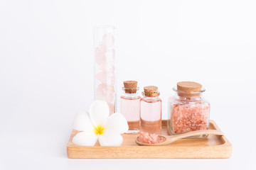Obraz na płótnie Canvas Spa and beauty treatment with rose liquid soap,pink Himalayan salt,rose quatz stones and Plumeria flowera on wooden tray over white background