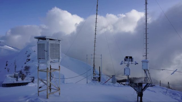 Snowy winter weather station in Caucasus mountains on moving clouds background. Time lapse.