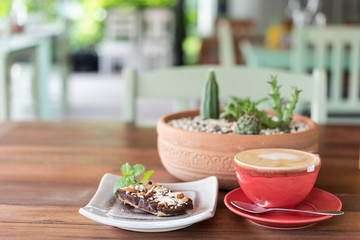 Red hot coffee cup and bakery on wood table at outdoor  restaurant