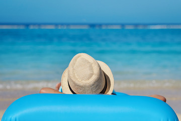 Cute European boy is enjoying his summer vacations on the seaside. He is laying on the blue inflatable floater.