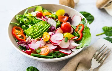 Foto auf Acrylglas Fresh vegetable salad bowl closeup, healthy organic vegetables salad with radish, spinach, tomatoes, onion, avocado © marrakeshh