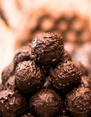 A tower display of fine dark chocolate truffles in a chocolate shop.