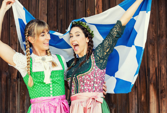 Junge Oktoberfest Bedienungen im Dirndl mit Bayern Fahne freudig
