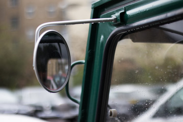 A wing mirror on a green classic van.