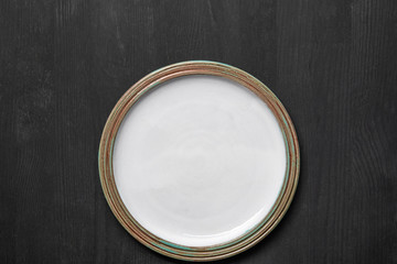 top view of vintage white empty round plate on black wooden table