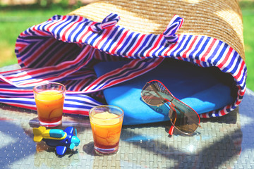 Summer picnic with straw beach bag on a table and two colorful orange desserts. Sunglasses and a toy plane. Vacation and travel concept with copy space