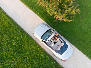 Aerial view of successful man driving and enjoying his silver convertible luxury sports car on the...