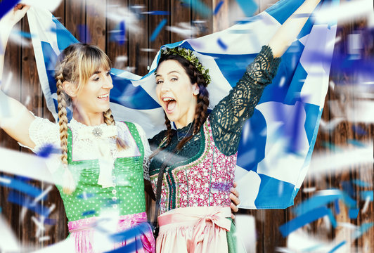junge h&uuml;bsche Frauen mit Dirndl und Bayernflagge feiern Oktoberfest