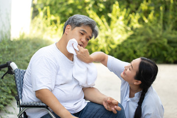 A physically handicapped young man needs a wheelchair because he can't help herself. The wife is encouraging and use a cloth to wipe the saliva at the mouth. He had the hope of recovering from illne.