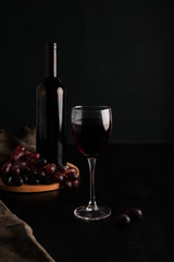 Glass of wine and a bottle of wine on a black background