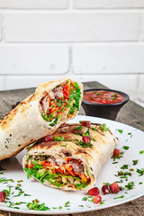 Close up delicious cuted shaurma or shawerma, kebab served on plate on wooden background. shawarma with meat, lettuce spices, and pickled cucumber. Eastern cuisine food with copy space. Fastfood