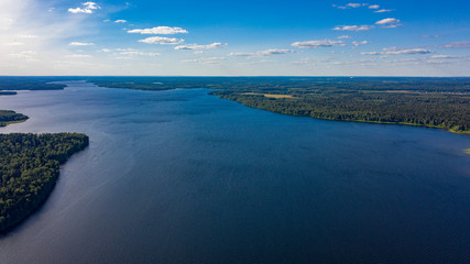 aerial photo of the big lake in the forest with cumulus clouds
