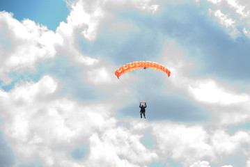 Skydivers is flying in the blue sky against the background of clouds.