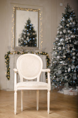 Classic Christmas decorated interior room New year tree. Christmas tree with gold decorations. Modern white classical style interior design apartment with fireplace and armchair.
