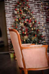 Classic Christmas decorated interior room New year tree. Christmas tree with gold decorations. Modern white classical style interior design apartment with fireplace and armchair.